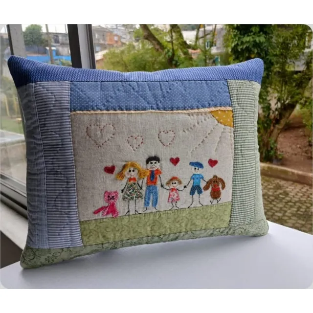 Almofada de patchwork com moldura azul e verde, quatro pessoas, um gato e um cachorro bordados